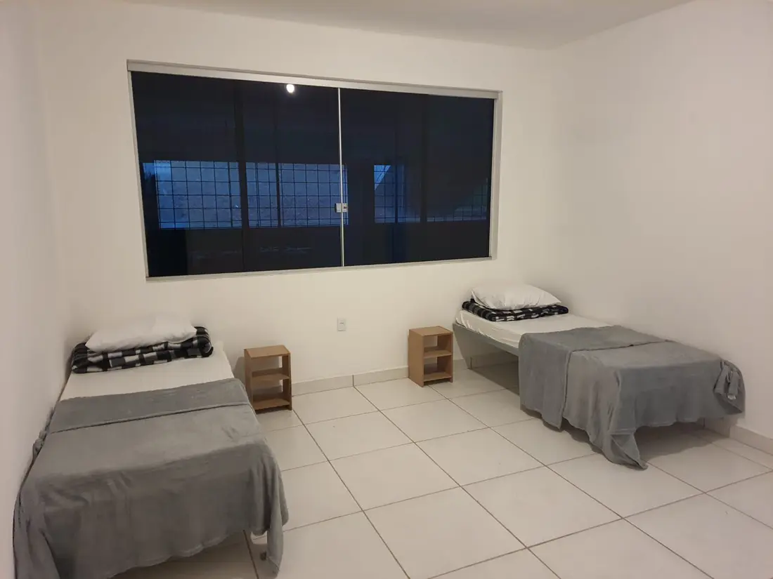 Quarto claro com duas camas de solteiro, criados-mudos e janela ampla