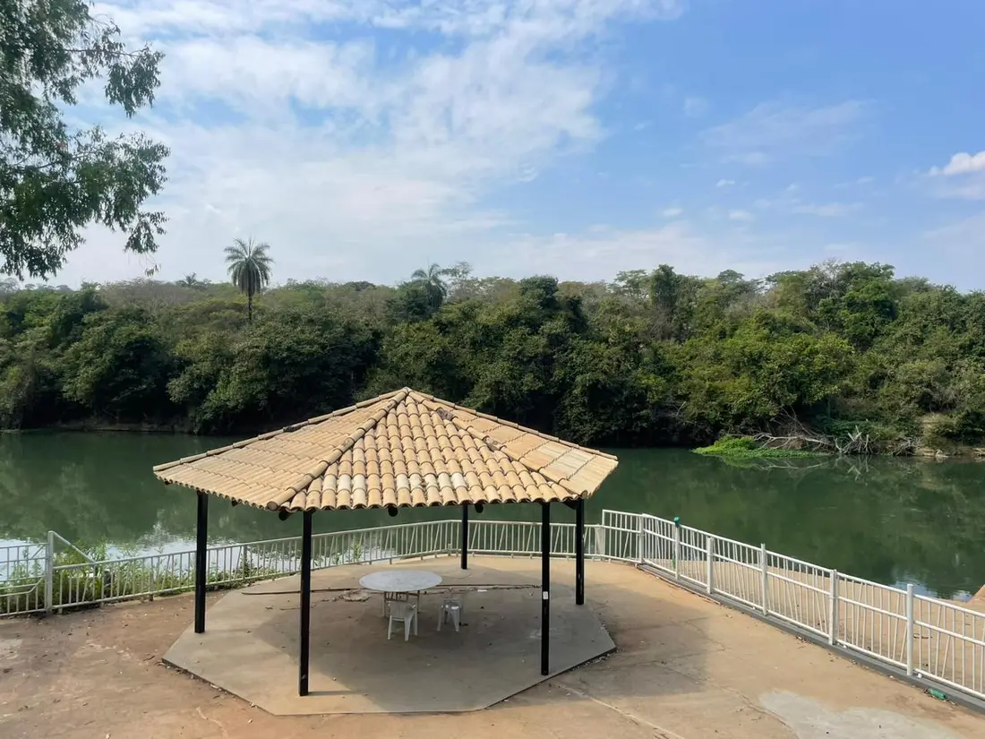 Quiosque de telhado de palha sobre deck, debruçado sobre um lago cercado de mata