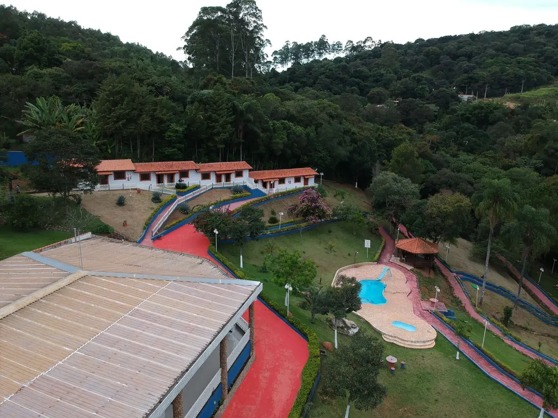 Vista aérea do complexo na encosta, com as construções, a piscina e os caminhos entre os jardins