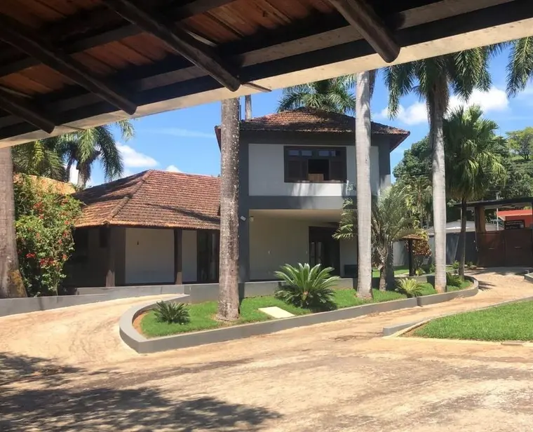 Sede de dois andares com telhado de barro, entre palmeiras e jardim