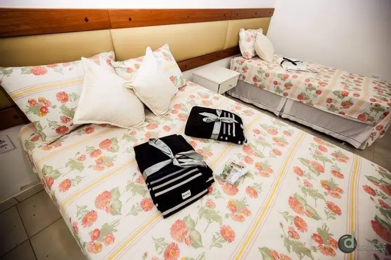 Cama arrumada com roupa de cama floral e toalhas dobradas