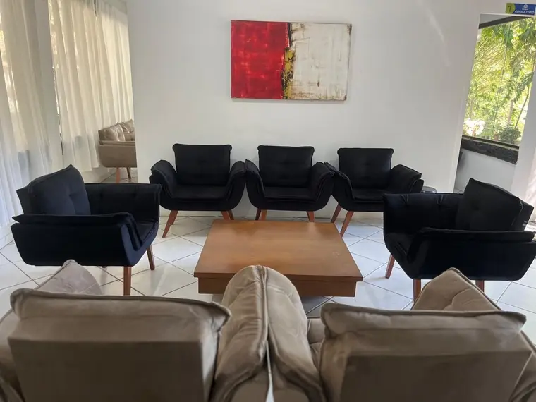 Sala de convivência com poltronas, sofás e mesa de centro