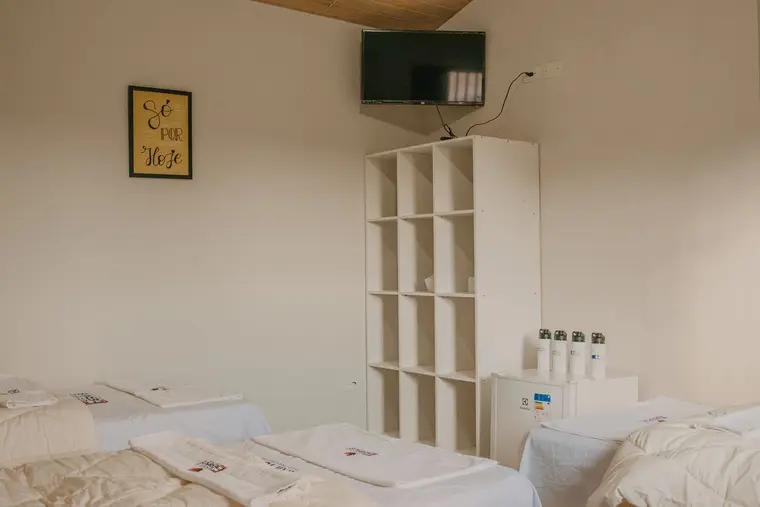 Quarto com camas, televisão e estante
