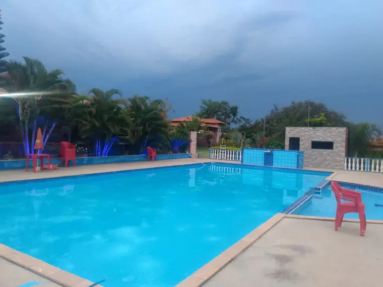 Piscina ampla de borda azul, com cadeiras na área externa