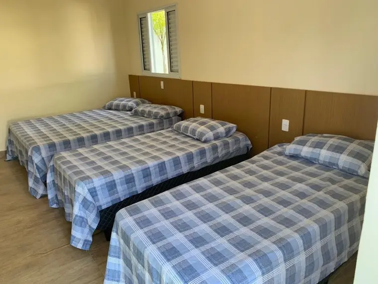 Quarto com duas camas de casal, cabeceira de madeira e roupa de cama xadrez