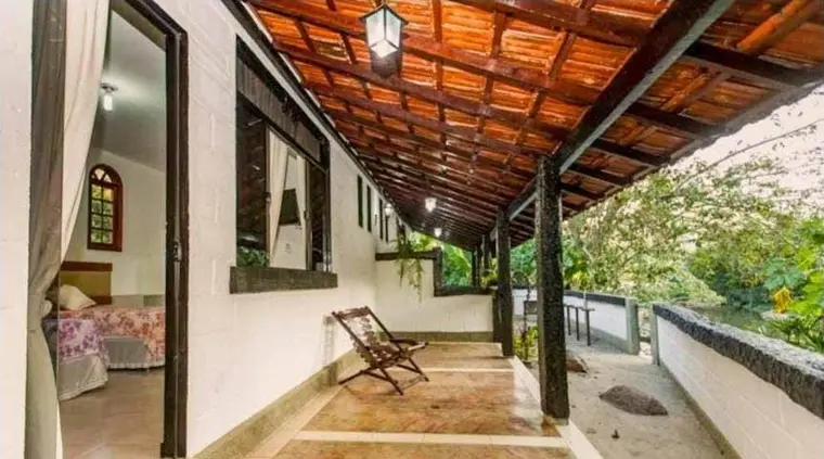Varanda coberta com estrutura de madeira, ligando os ambientes da casa