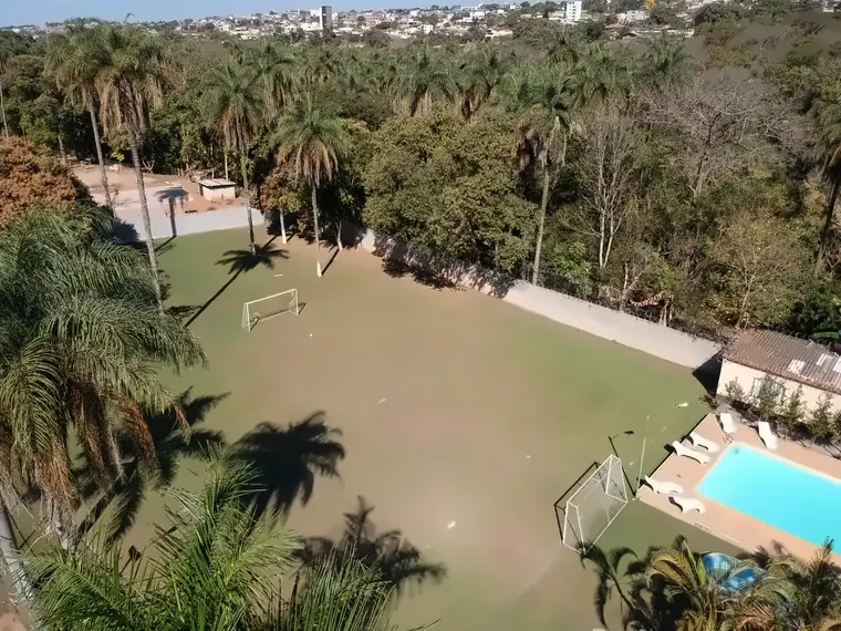 Vista aérea do campo de futebol em grama, com traves e árvores ao redor