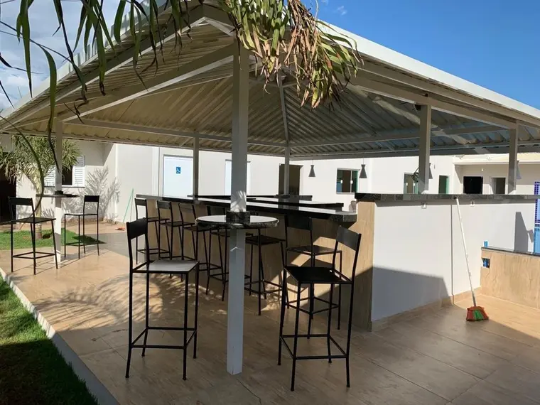 Lounge coberto com mesas altas e banquetas, aberto para a área externa