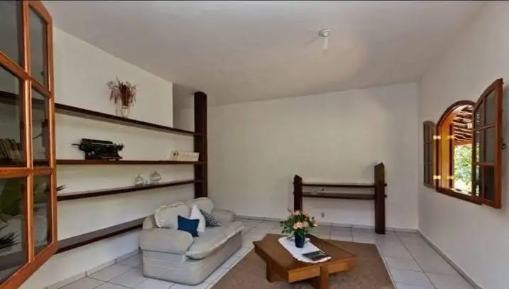 Sala de estar com sofá e janelas voltadas para o jardim