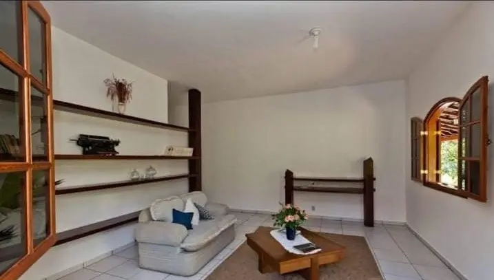 Sala de estar com sofá, tapete e janelas em arco voltadas para o jardim