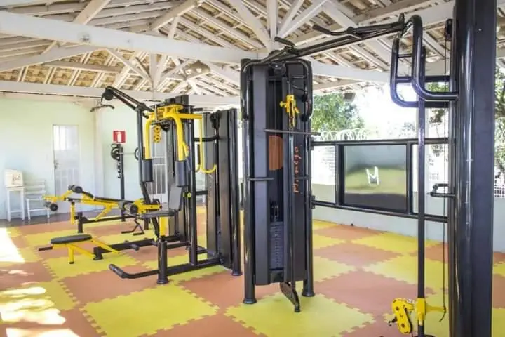 Academia coberta com estação de musculação, halteres e piso emborrachado