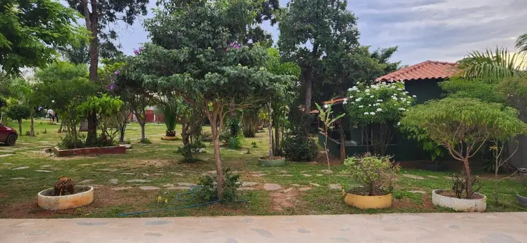 Jardim com canteiros, árvores e a sede ao fundo