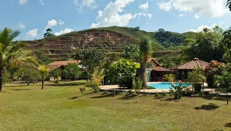 Jardim gramado com a piscina ao fundo e o morro ao longe
