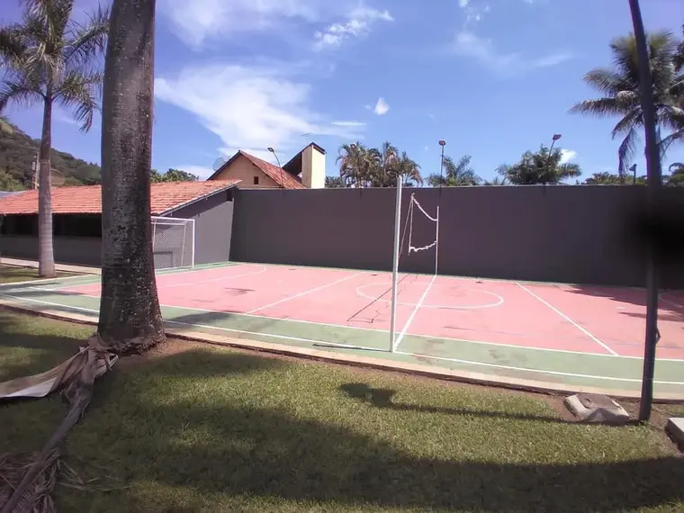Quadra poliesportiva com piso pintado, rede de vôlei e alambrado