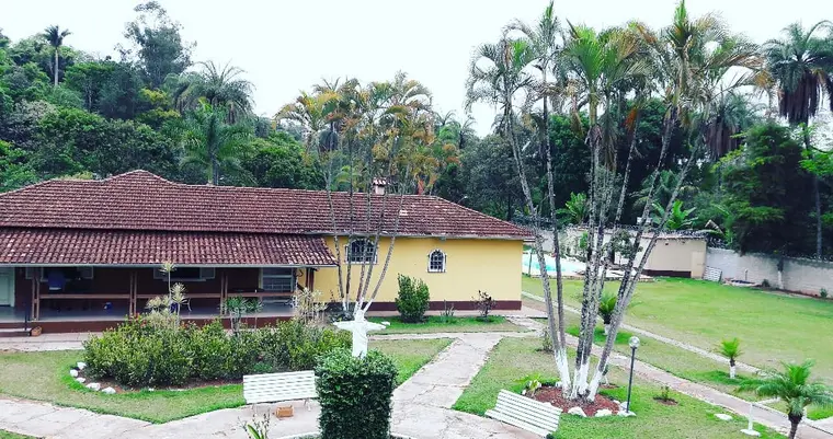 Fachada lateral da sede, com jardim, caminhos e a piscina ao fundo