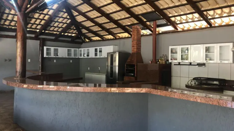 Cozinha ampla com bancada de granito, churrasqueira de tijolo e armários