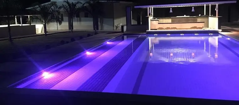 Piscina iluminada à noite, vista da área de convivência