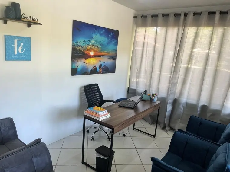 Sala de atendimento com mesa, poltronas e boa entrada de luz