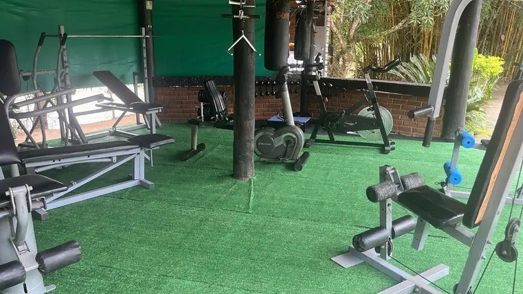 Academia coberta com aparelhos de musculação e piso em grama sintética