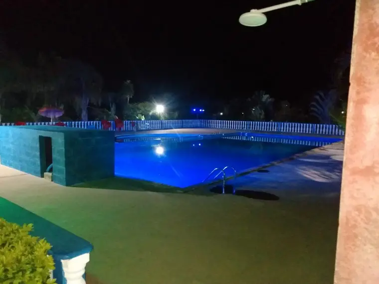 Piscina iluminada ao anoitecer, vista da área de convivência