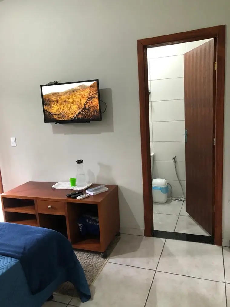 Quarto com cama, criado-mudo, televisão e banheiro privativo