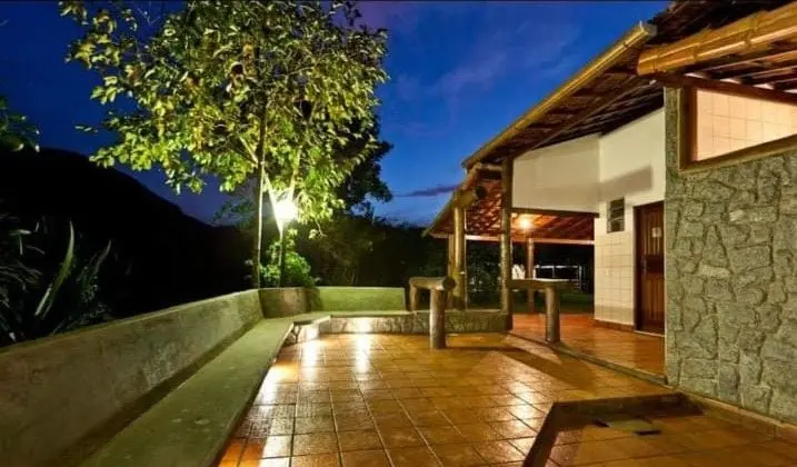Área externa iluminada ao anoitecer, com varanda e piso de cerâmica