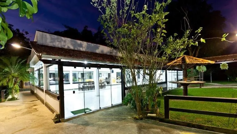 Área externa iluminada ao anoitecer, com deck e vista para a piscina