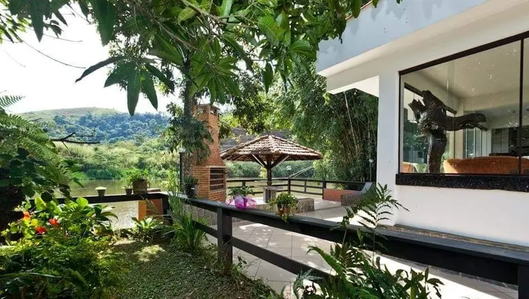 Jardim com guarda-sol, canteiros floridos e vista para a mata