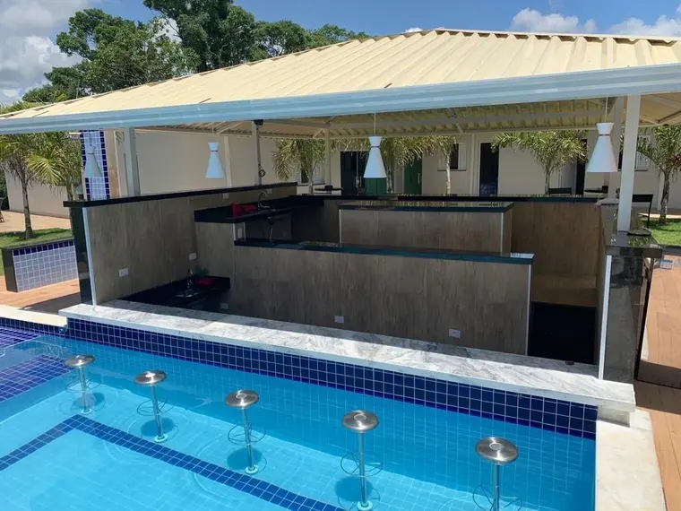 Bar coberto visto de dentro da piscina, com bancada e iluminação