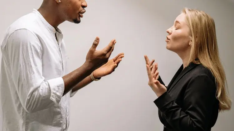 Duas pessoas discutindo de pé, uma de frente para a outra