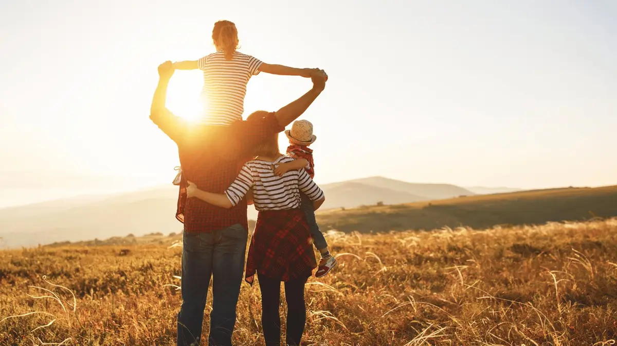 Família caminhando abraçada em um campo ao entardecer