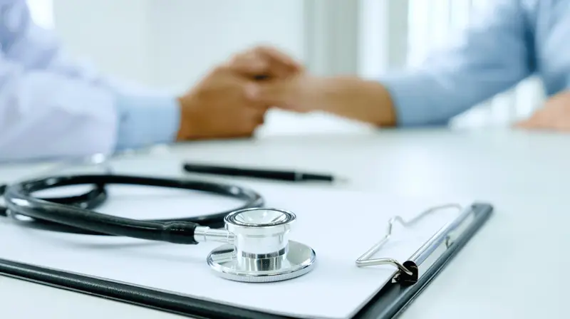Mesa de consultório com estetoscópio e prancheta durante um atendimento