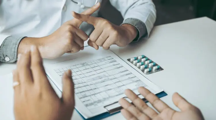Mãos preenchendo um formulário ao lado de cartelas de medicamento